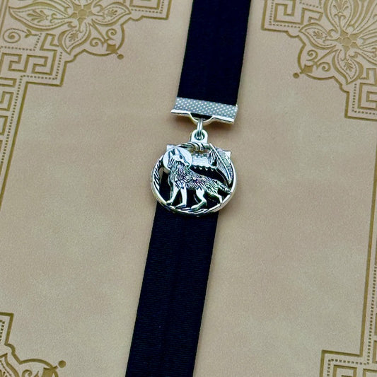 A silver wolf howling at the moon charm on a elastic Bookband