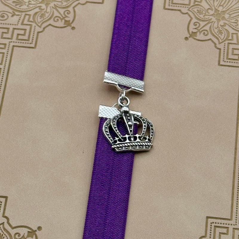 A silver royal crown charm on an elastic Bookband