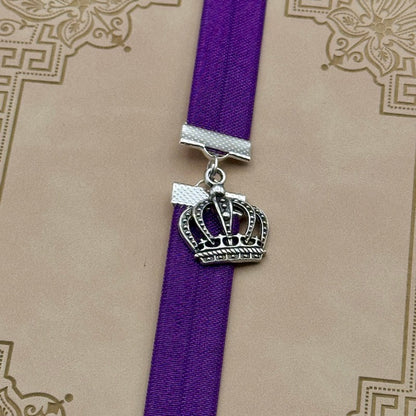 A silver royal crown charm on an elastic Bookband
