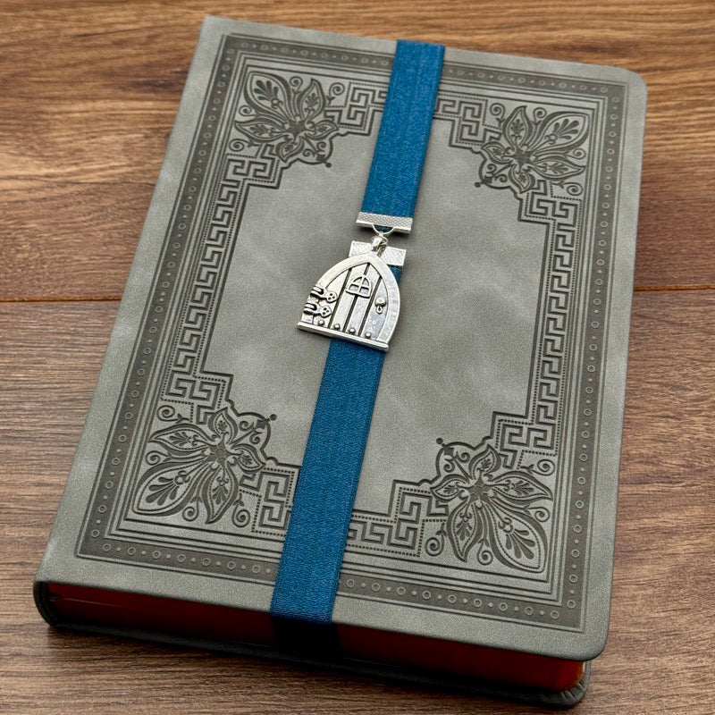 A silver arched door charm on an elastic Bookband