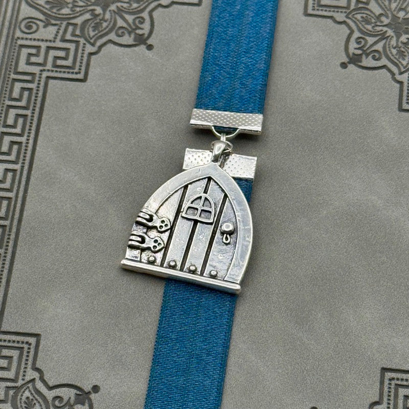 A silver arched door charm on an elastic Bookband