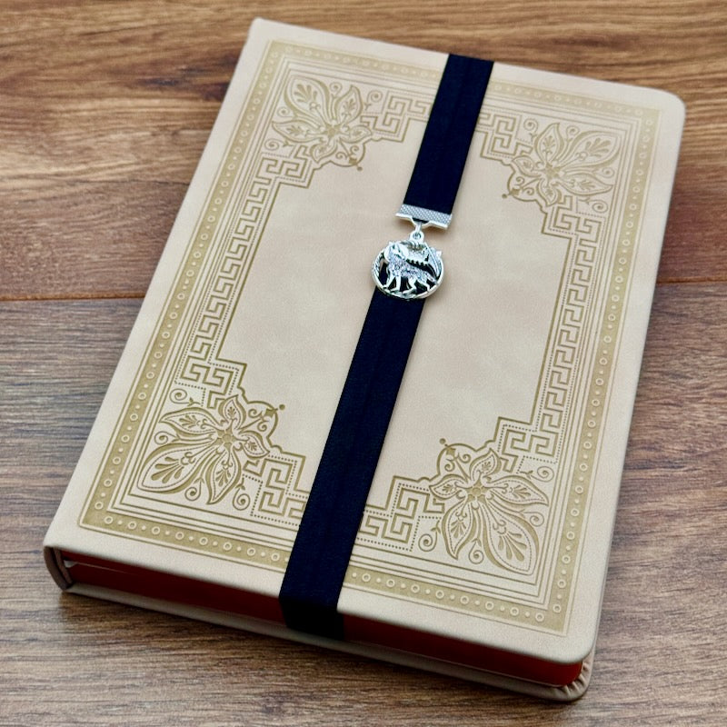 A silver wolf howling at the moon charm on a elastic Bookband