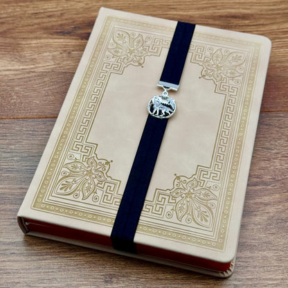 A silver wolf howling at the moon charm on a elastic Bookband