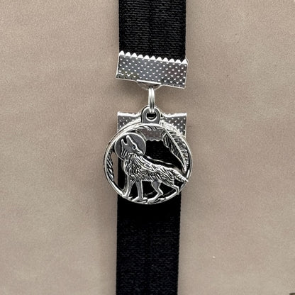 A silver wolf howling at the moon charm on a elastic Bookband