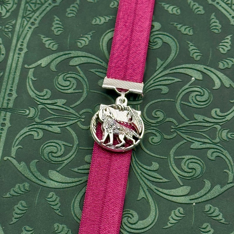 A silver wolf howling at the moon charm on a elastic Bookband