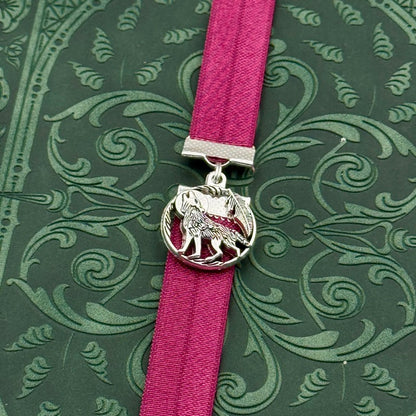A silver wolf howling at the moon charm on a elastic Bookband