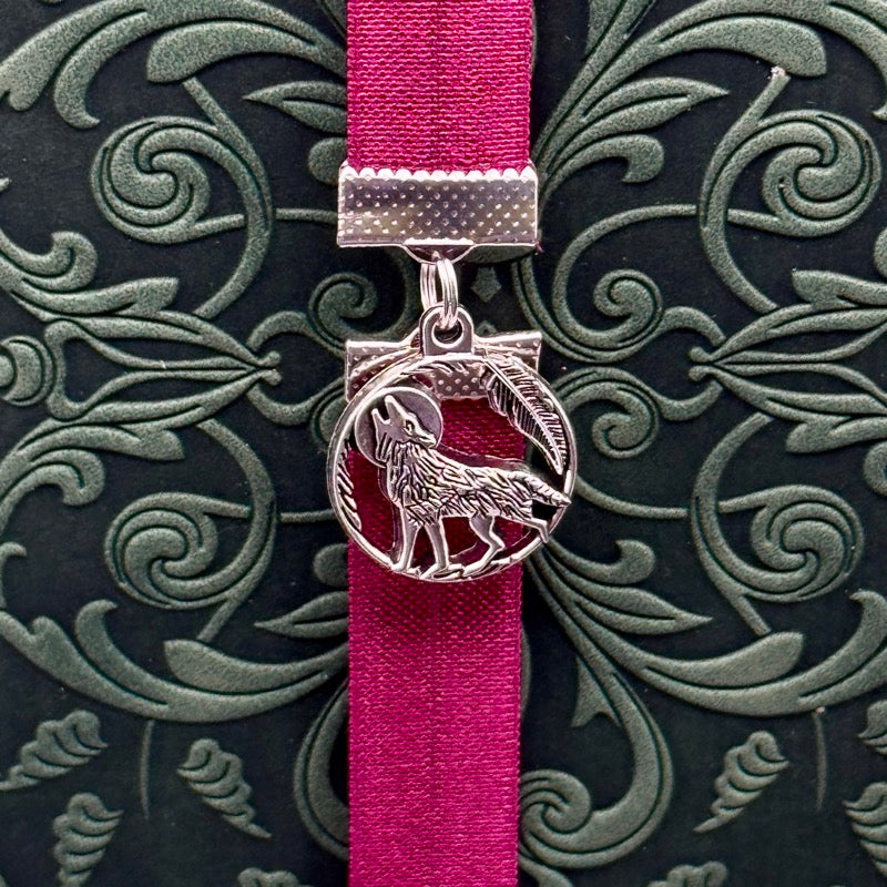 A silver wolf howling at the moon charm on a elastic Bookband