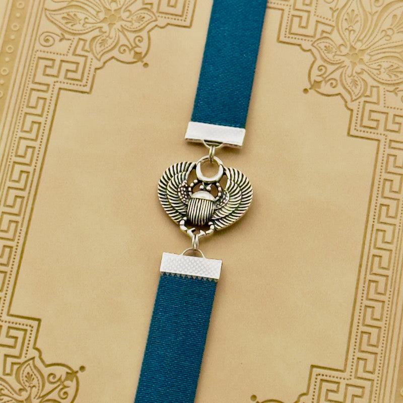 A silver scarab beetle charm on a elastic Bookband