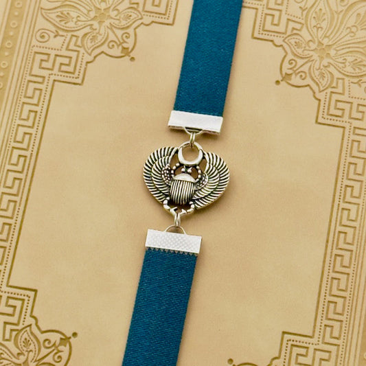 A silver scarab beetle charm on a elastic Bookband
