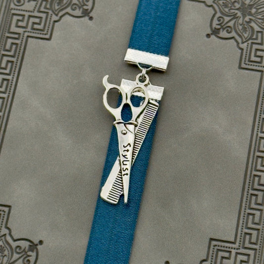 A silver hairstylist scissors and comb charm on a elastic Bookband