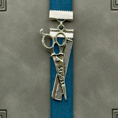 A silver hairstylist scissors and comb charm on a elastic Bookband