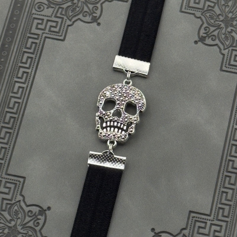 A silver cubic zirconia Sugar Skull charm on a elastic Bookband