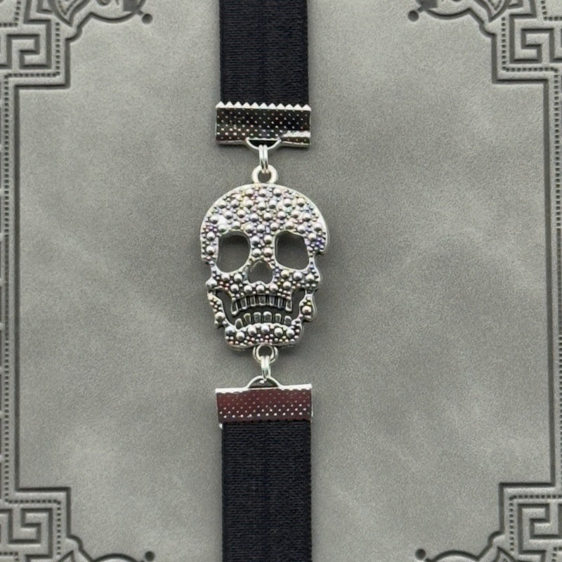A silver cubic zirconia Sugar Skull charm on a elastic Bookband