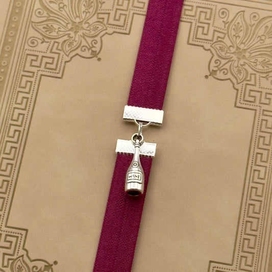 A silver wine bottle charm on an elastic Bookband