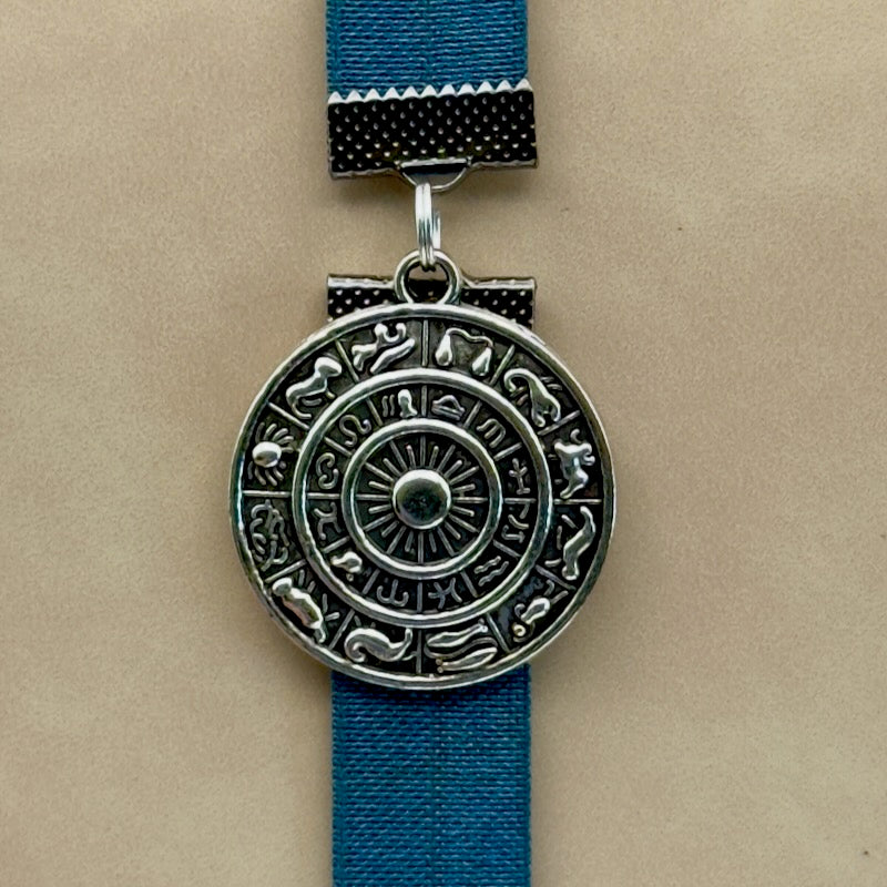 A silver zodiac charm on an elastic Bookband