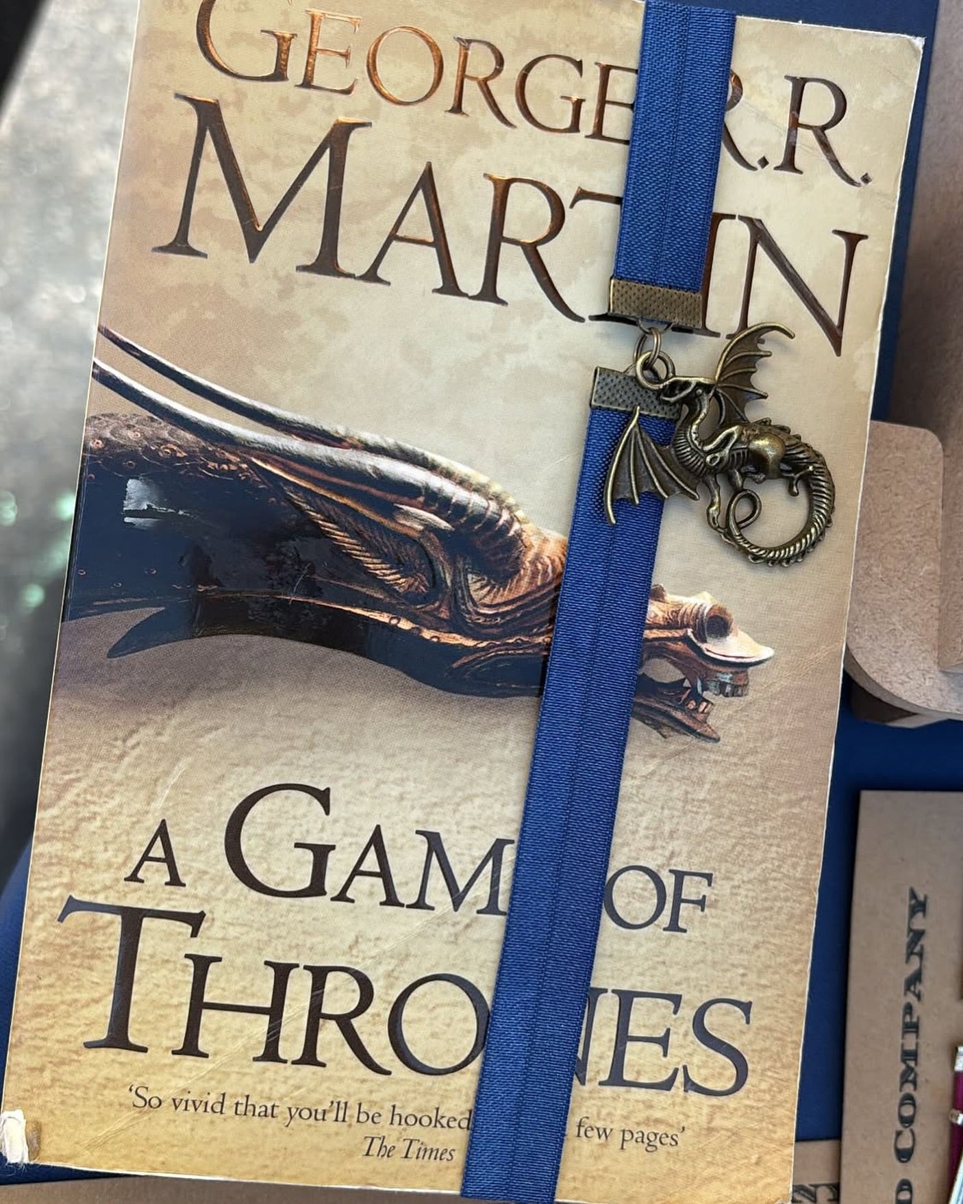 Book of 'A Game of Thrones' by George R.R. Martin with a dragon-themed elastic bookband bookmark.