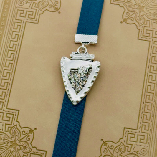 A silver arrowhead, with a howling wolf in the centre, charm on a elastic Bookband