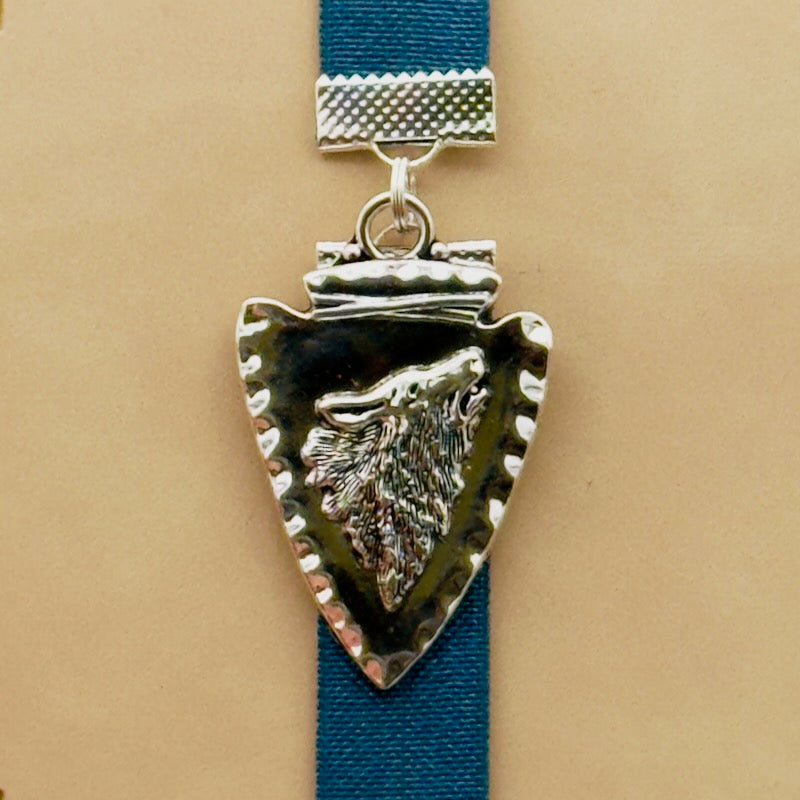A silver arrowhead, with a howling wolf in the centre, charm on a elastic Bookband
