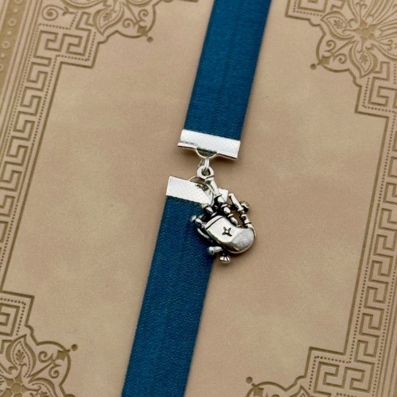 A silver bagpipes charm on a elastic Bookband