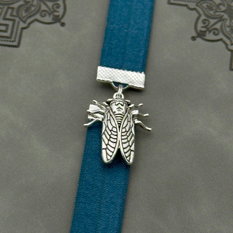 A silver cicada charm on a elastic Bookband