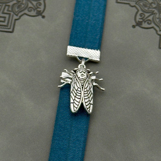 A silver cicada charm on a elastic Bookband
