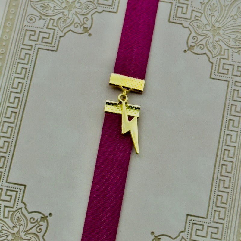 A gold lightning bold charm on an elastic Bookband
