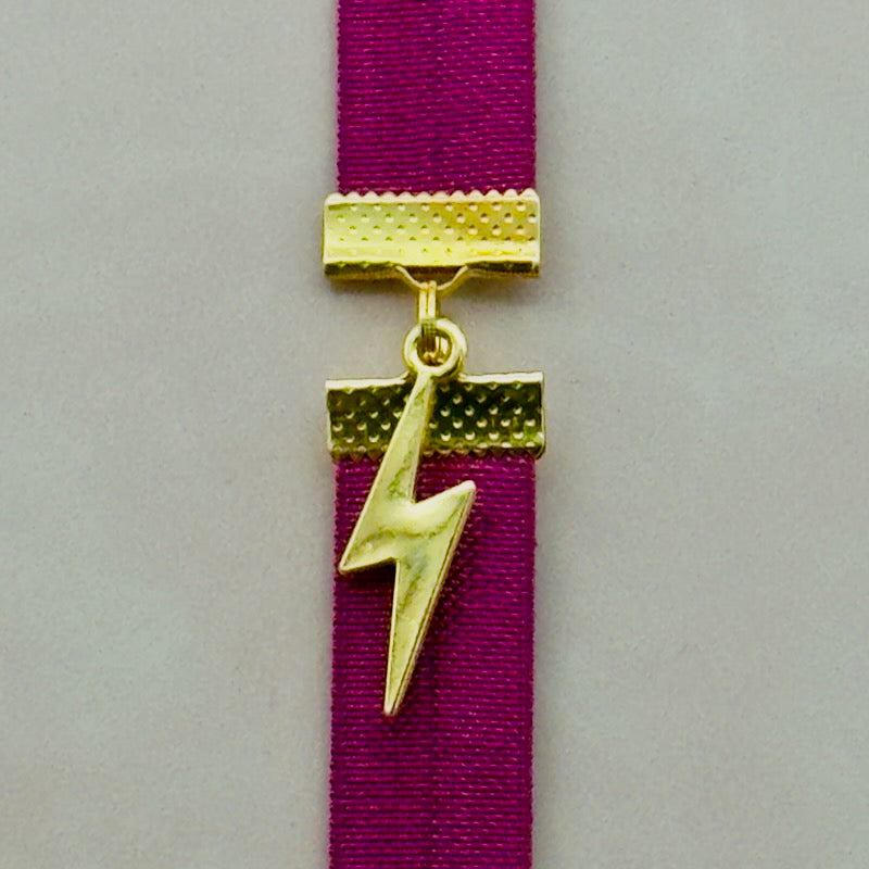 A gold lightning bold charm on an elastic Bookband